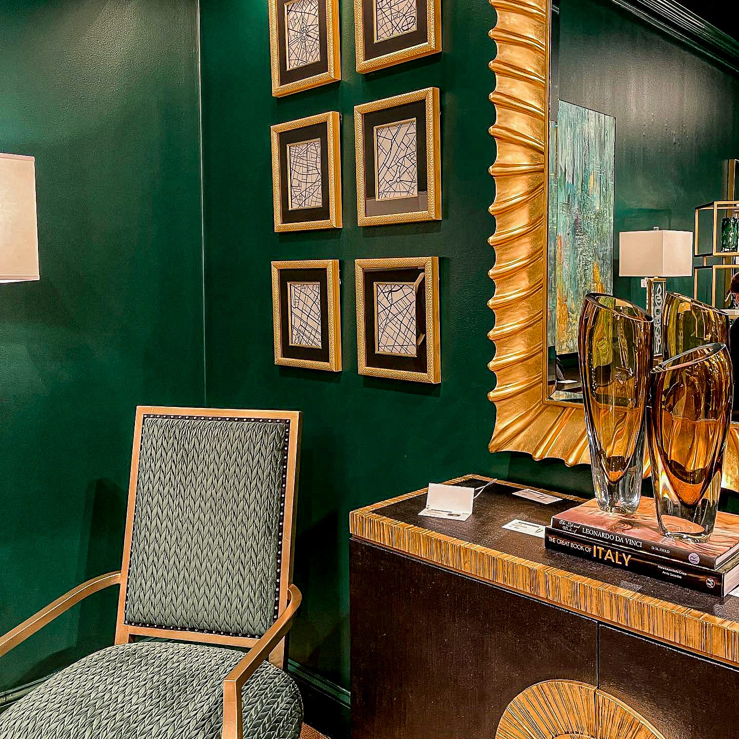 green wall room with a chair and gold framed pictures hanging on the walls