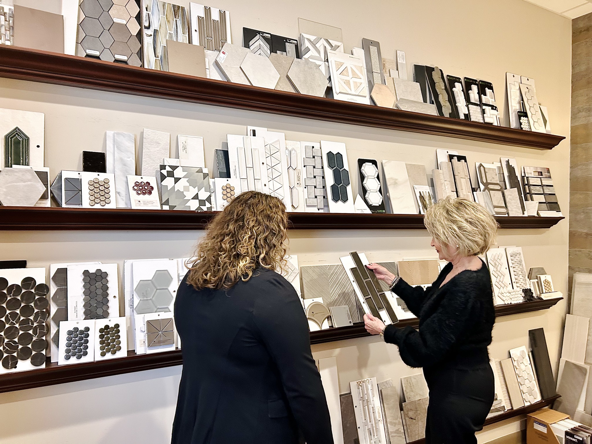 two female interior decorators looking at items on a wall at interiors joan and associates in lincoln